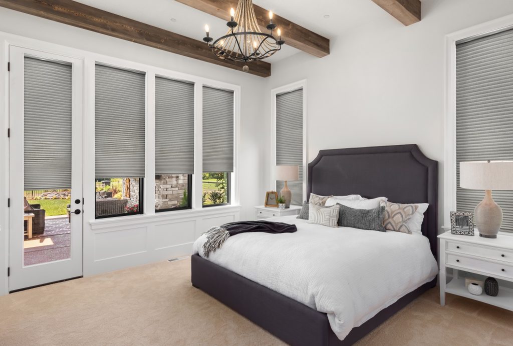 Grey honeycomb cellular shades in a bright, rustic-style bedroom for insulation and privacy.