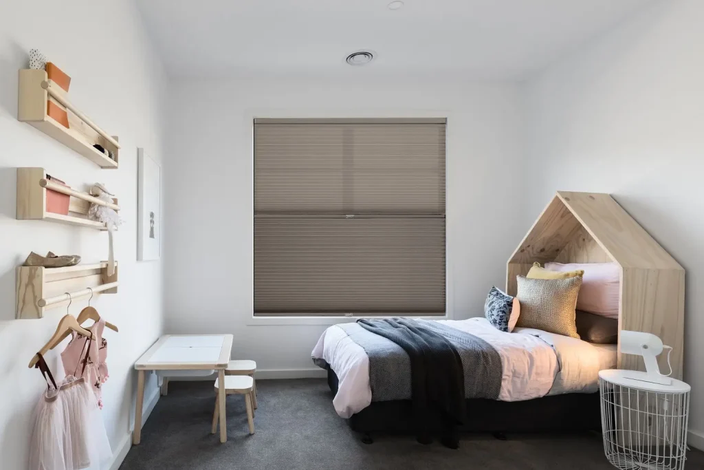 Children’s bedroom with energy-efficient honeycomb window shade in soft neutral tones.